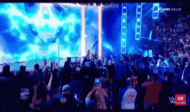 a crowd of people are watching a wrestling match on a television