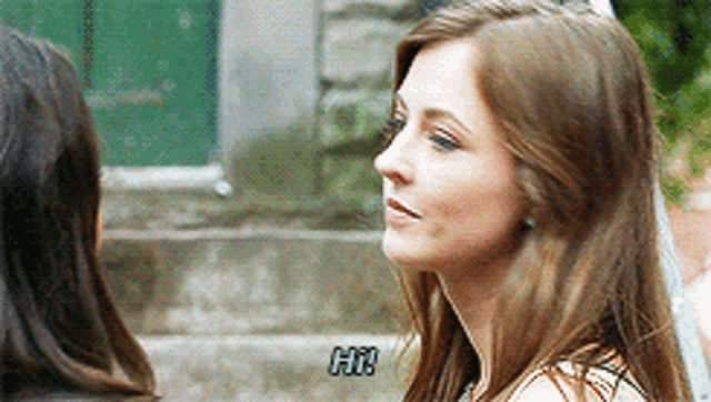 a woman says hi to another woman in front of a building .