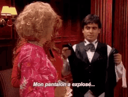 a man in a tuxedo is talking to a woman who is wearing a pink dress