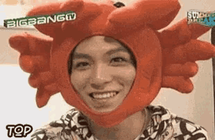 a man wearing a red crab hat is smiling and looking at the camera .