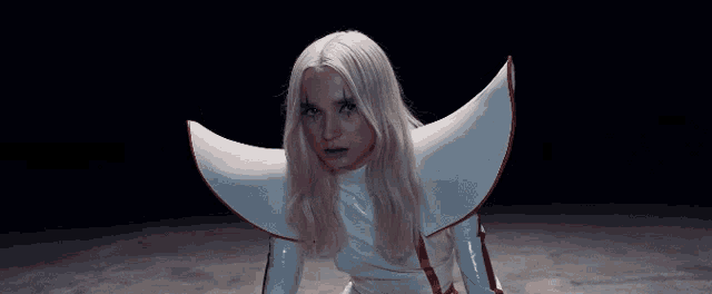 a woman with long blonde hair is sitting in a white chair