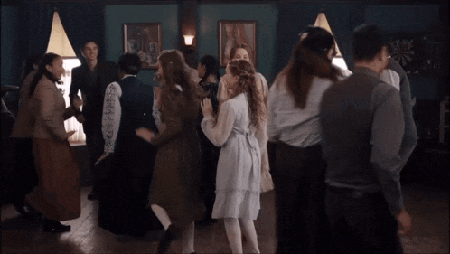 a group of people are dancing in a room with a dart board