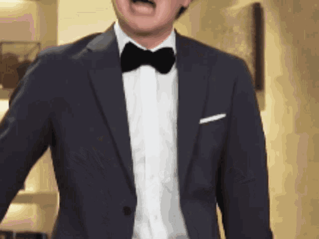 a man in a tuxedo and bow tie is screaming