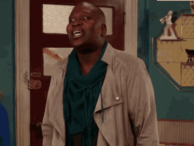 a man wearing a scarf and a jacket is standing in front of a red door