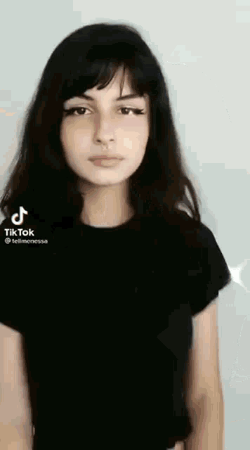 a girl with long hair and a nose ring is wearing a black shirt and looking at the camera .