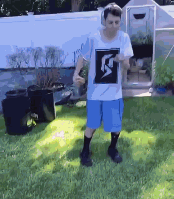 a man wearing headphones and a shirt with a lightning bolt on it is standing in the grass