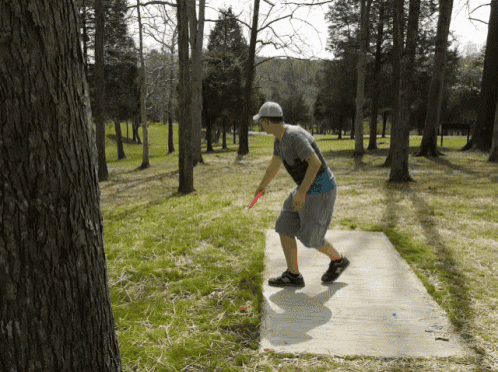 a man throwing a frisbee on a disc golf course