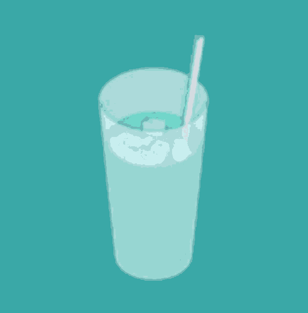 a glass of green liquid with ice and a straw .