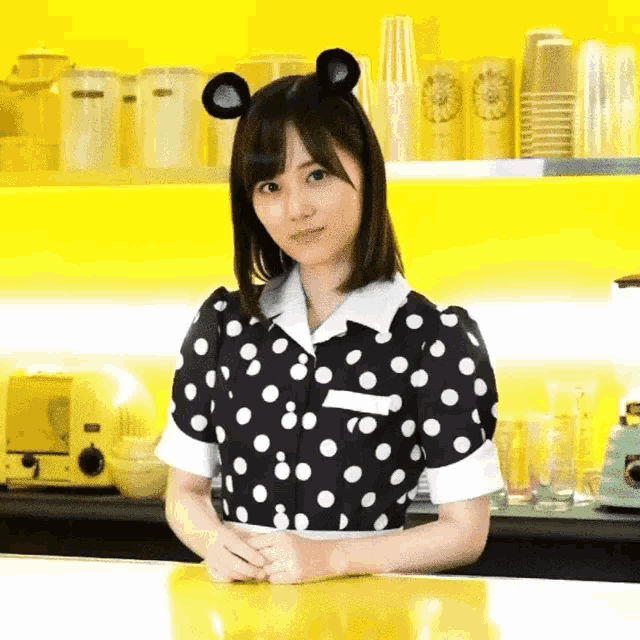 a woman in a black and white polka dot dress with mouse ears on her head