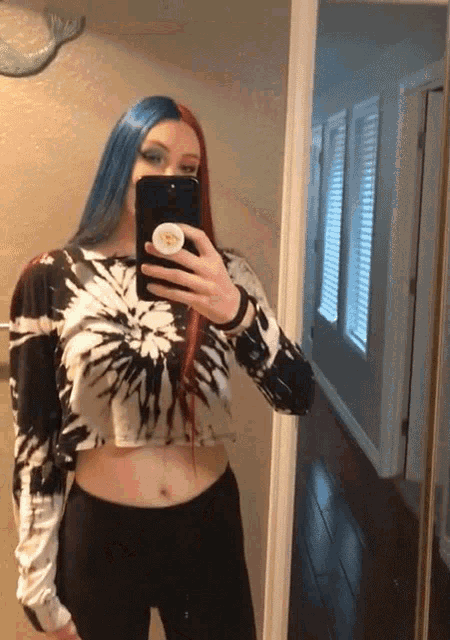 a woman in a tie dye shirt takes a selfie