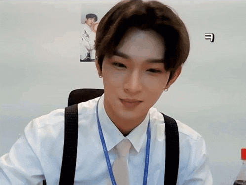 a man wearing suspenders and a lanyard with the letter e on it looks at the camera