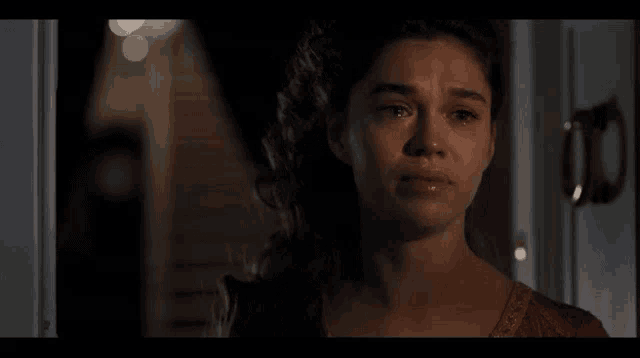 a woman is standing in front of a door in a dark room and looking at the camera .