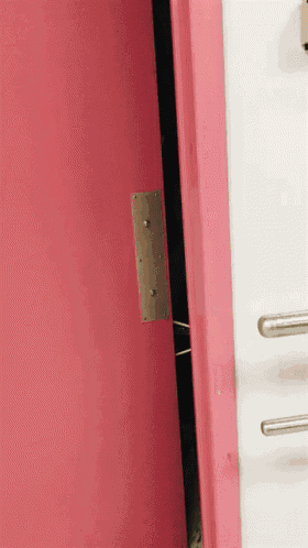 a close up of a pink door with a metal plate on it
