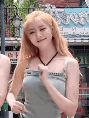 a woman with blonde hair is wearing a blue tank top and overalls .