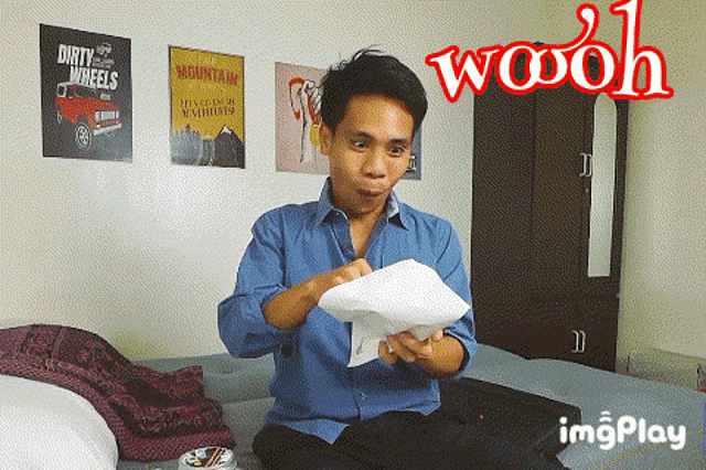 a man sitting on a bed holding a piece of paper with the word woooh above him