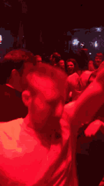 a man in a red shirt is dancing in a club