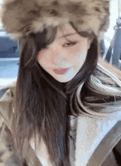 a close up of a woman wearing a fur hat and a coat .