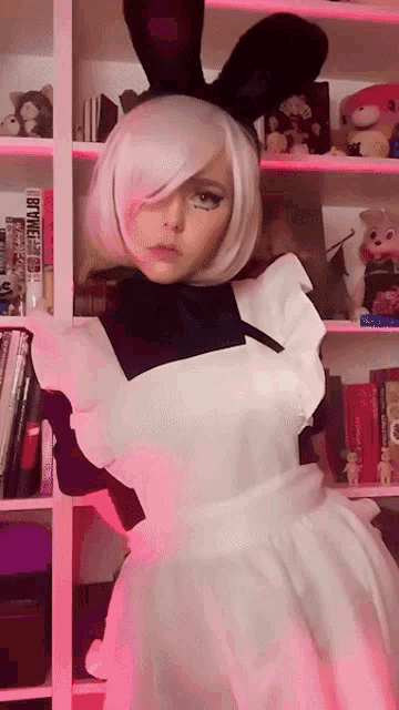 a girl in a maid costume is standing in front of a bookshelf with a book titled tokyo ghoul
