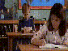 a boy and a girl are sitting at desks in a classroom writing