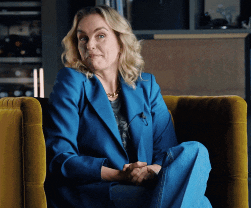 a woman in a blue jacket sits on a yellow chair