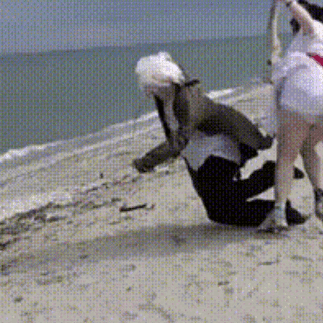 a man and a woman are kneeling on a beach