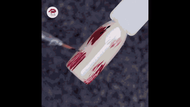 a bottle of nail polish is being applied to a nail with a red brush