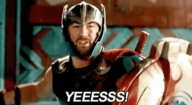 a man in a superhero costume is holding a shield and a helmet .