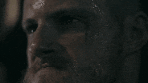 a close up of a man 's face with a beard and a bloody eye