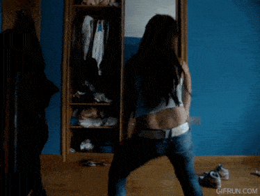 a woman is dancing in front of a mirror with gifrun.com written on the bottom