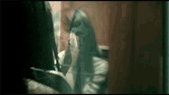 a woman is looking at herself in a mirror and covering her face .