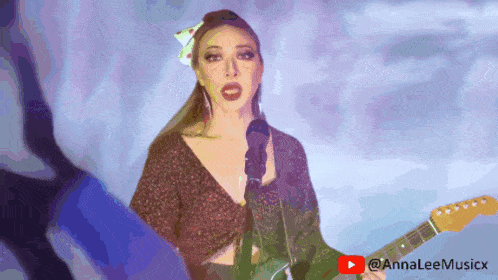 a woman is singing into a microphone while holding a guitar with a youtube logo in the background