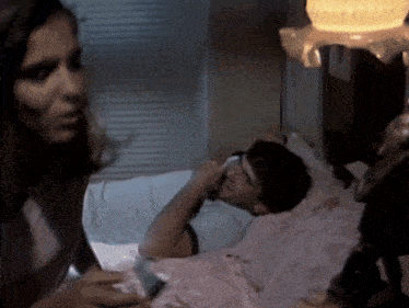 a man laying in a bed with a woman standing next to him