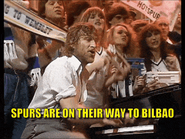 a man playing a piano in front of a crowd with the words spurs are on their way to bilbao