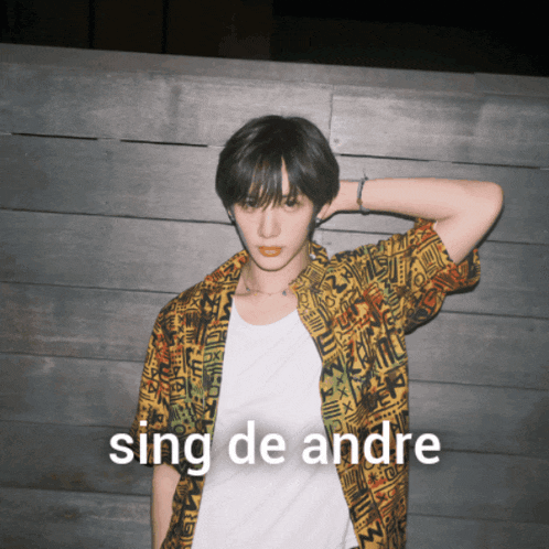 a man in a colorful shirt is standing in front of a wooden wall with the words sing de andre above him