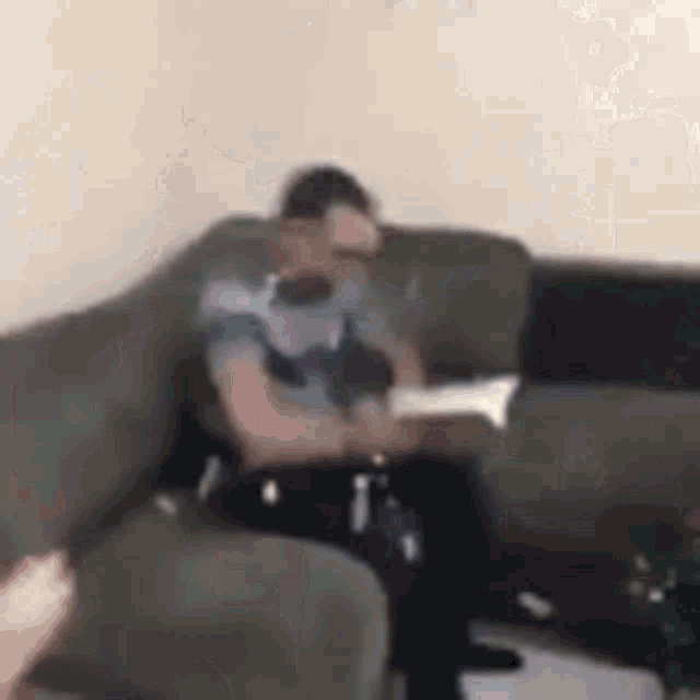 a man is reading a book while sitting on a couch in a living room .