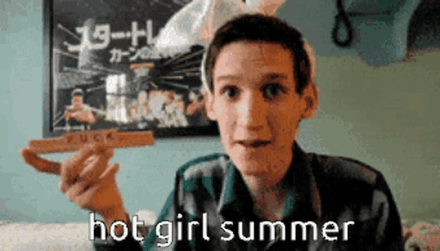 a young boy holding a piece of wood with the words hot girl summer written on it