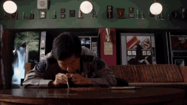 a man sits at a table in front of a sign that says america 's consistent