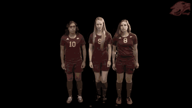 three female soccer players are jumping in the air with their hands in the air