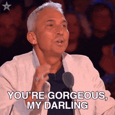 a man speaking into a microphone with the words you 're gorgeous my darling below him