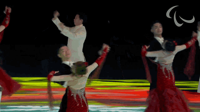 a group of people are dancing on a stage with a paralympic logo in the background