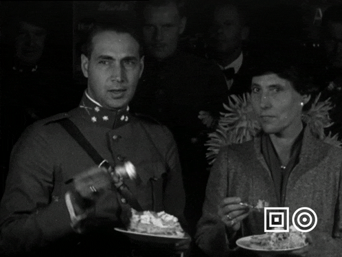 a black and white photo of a man and a woman holding plates of food