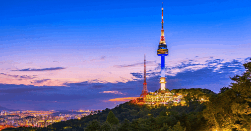 a tower on top of a hill with a city behind it