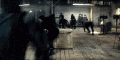 a group of people are standing in a dark room with a wooden floor .