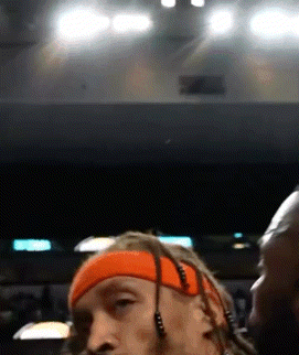 a man with dreadlocks wearing an orange headband and earbuds