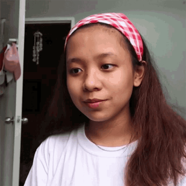 a young girl wearing a white shirt and a headband looks at the camera