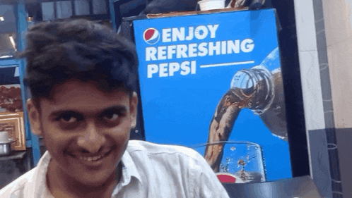 a man stands in front of a pepsi advertisement