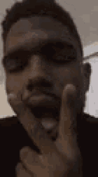 a man is making a funny face while holding his hand to his face .