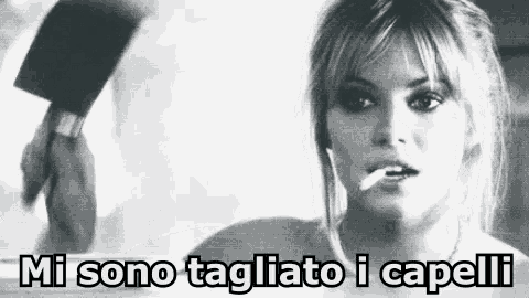 a woman is smoking a cigarette in a black and white photo with the words mi sono tagliato i capelli written below her .