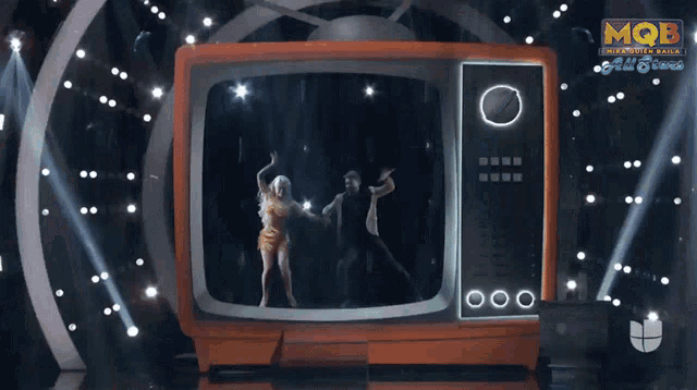 a man and a woman are dancing in front of a tv that says mqb