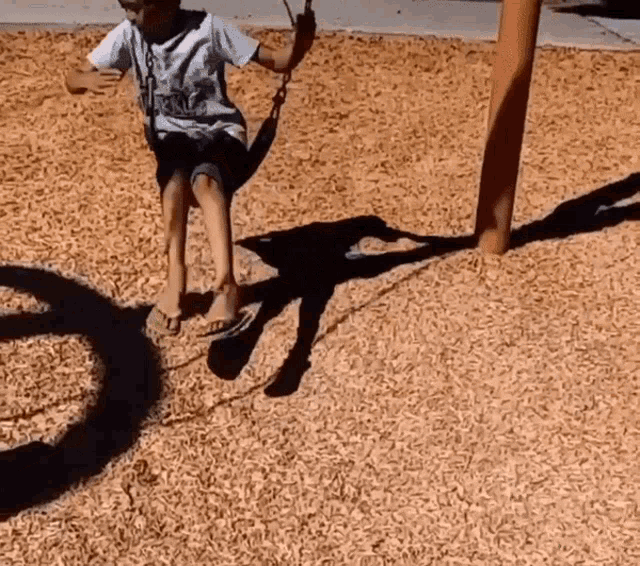 a young boy is swinging on a swing with a shirt that says ' royals ' on the front